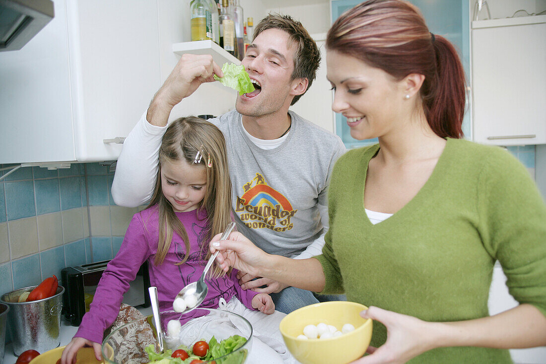 Young family preparing a salad in a domestic kitchen, Munich, Germany