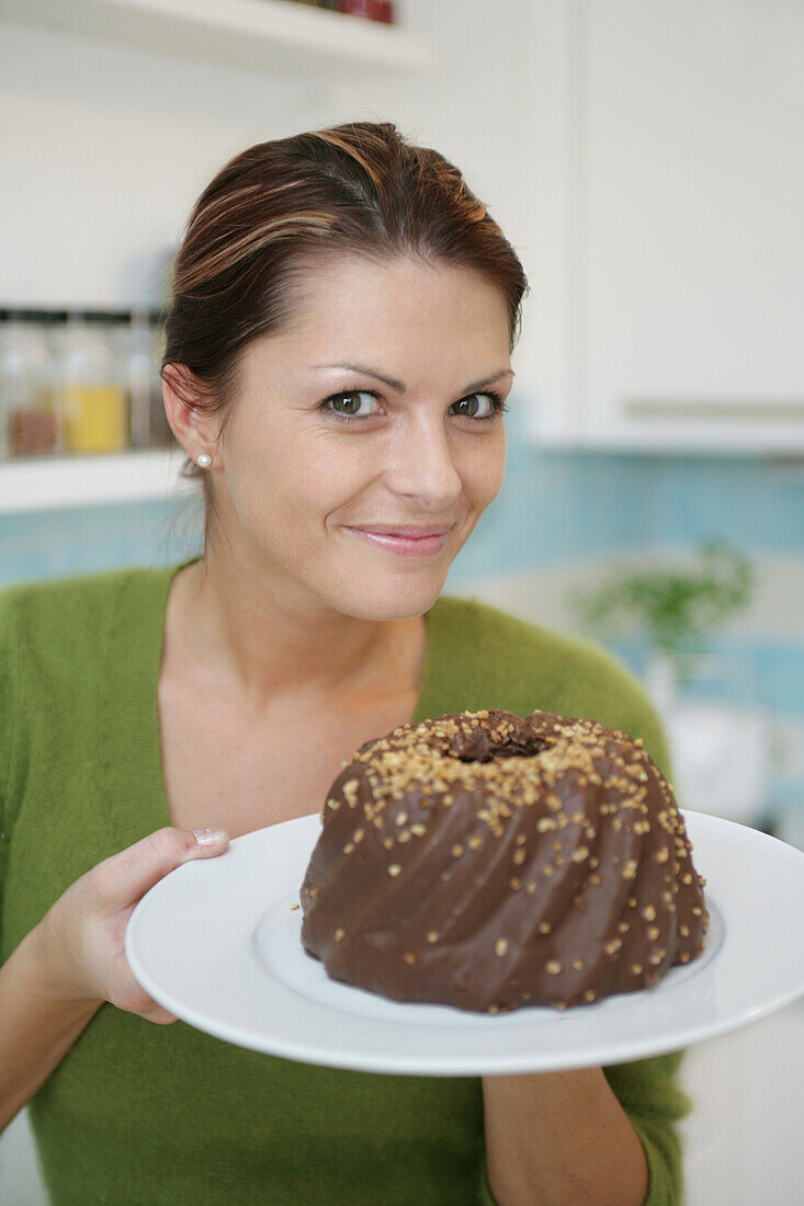 Junge Frau hält einen Schokoladenkuchen, München, Deutschland