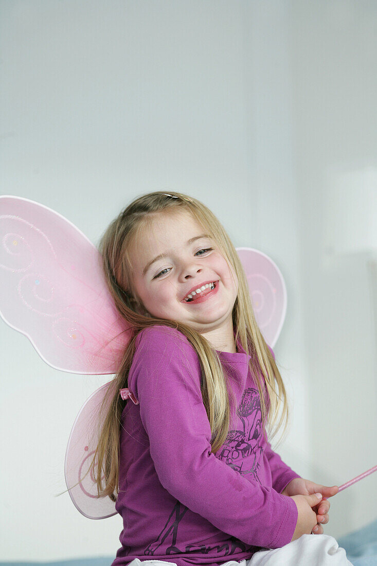 Girl (3-4 years) wearing butterfly wings holding wand, Munich, Germany