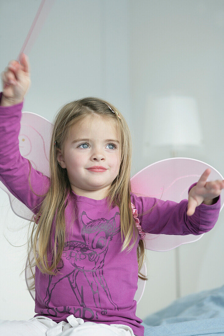 Girl (3-4 years) wearing butterfly wings holding wand, Munich, Germany