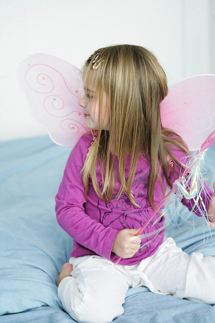 Girl (3-4 years) wearing butterfly wings holding wand, Munich, Germany