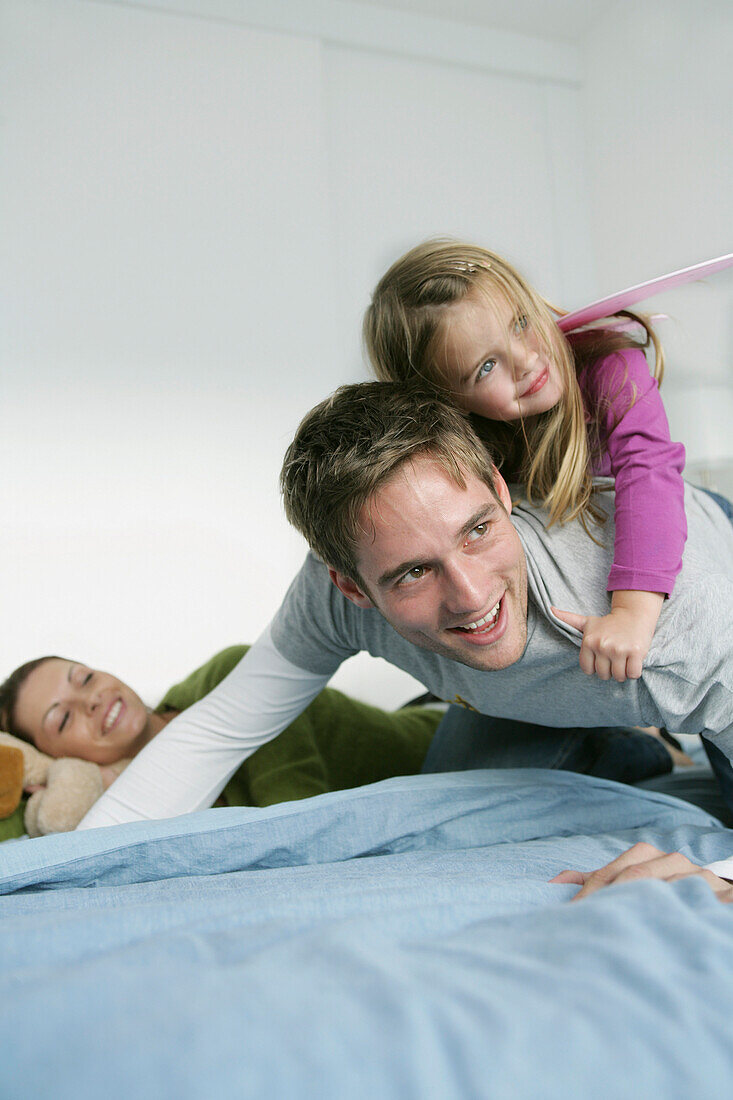 Junge Familie spielt auf einem Bett, München, Deutschland