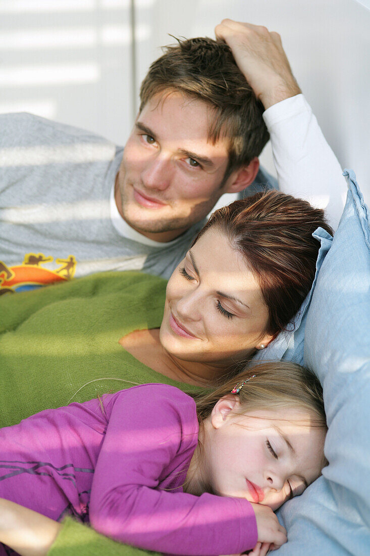 Young family lying on bed, mother and daughter sleeping, Munich, Germany