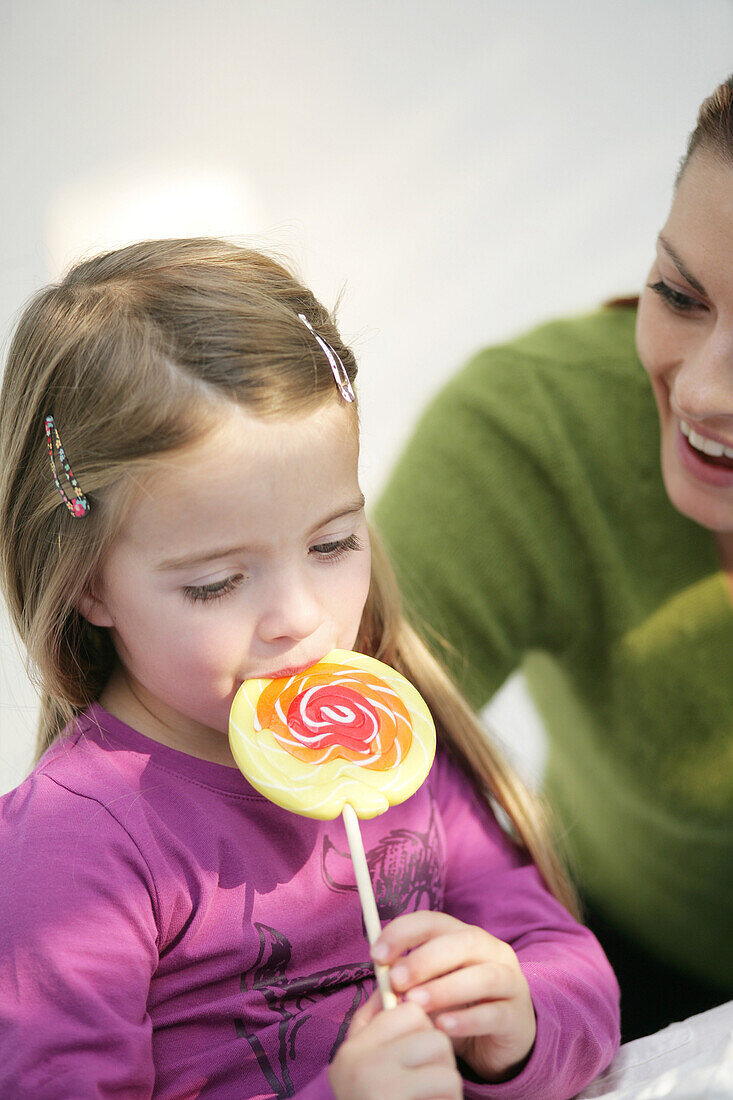Girl (3-4 years) licking a lollipop, Munich, Germany