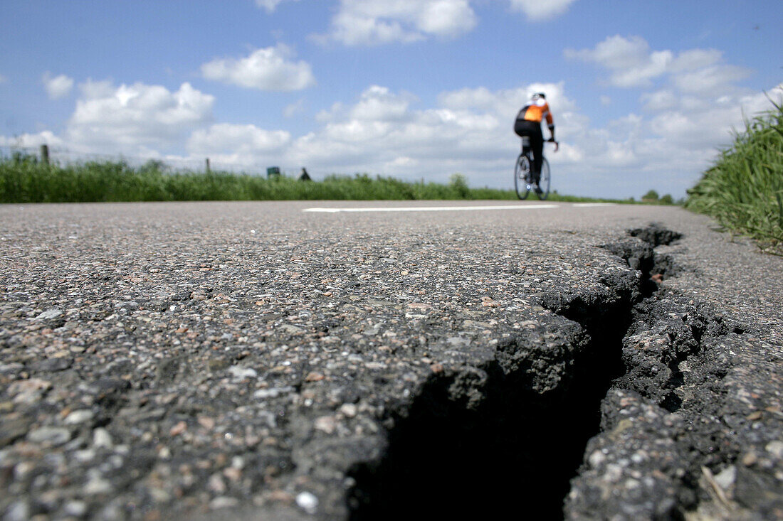 Broken asphalt road and biker.