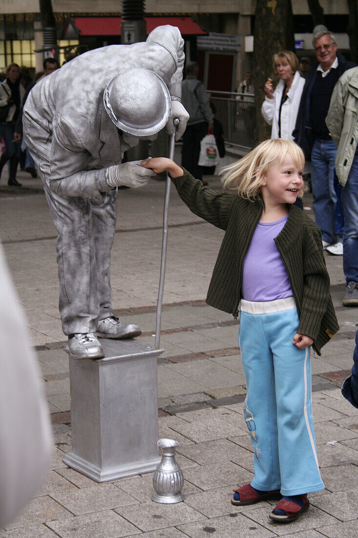 Silver street performer, artist performing with girl, Shopping street, Hamburg, Germany