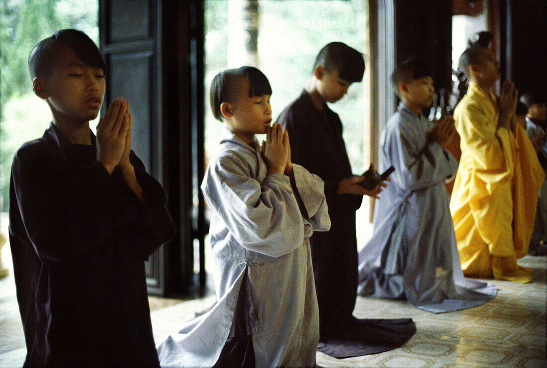 Child monks praying in Tu Hieu Temple, Hue, Vietnam, Indochina, Asia