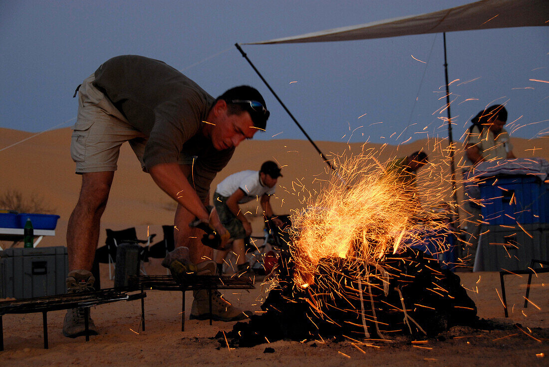 Mann zündet Lagerfeuer an, Zelten in der Wüste, Offroad 4x4 Sahara Reisen, Wüsten Tour, Bebel Tembain, Sahara, Tunesien, Afrika, mr