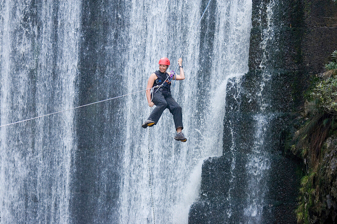Frau hängt an einem Seil vor einem Wasserfall, Grabouw Forest Park, Südafrika