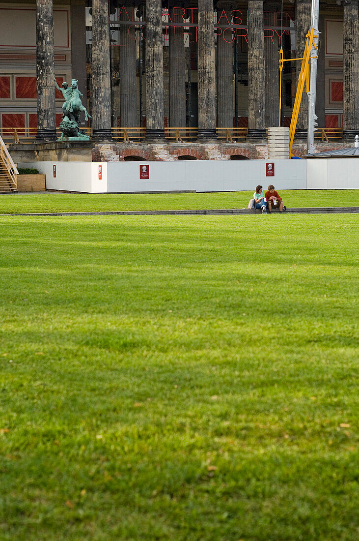 Teo people sitting on the grass outside the Old Museum, renovation work, Berlin, Germany