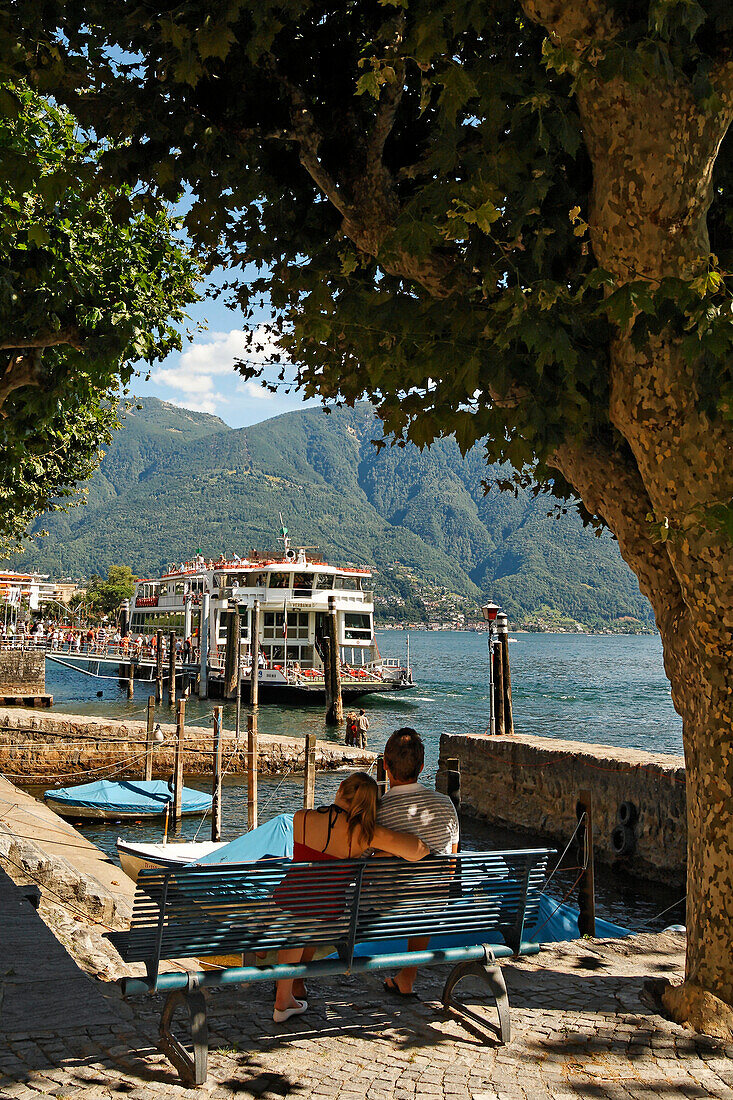 Schweiz Ascona Lago Maggiore Seeufer, Paar auf Bank, Faehre