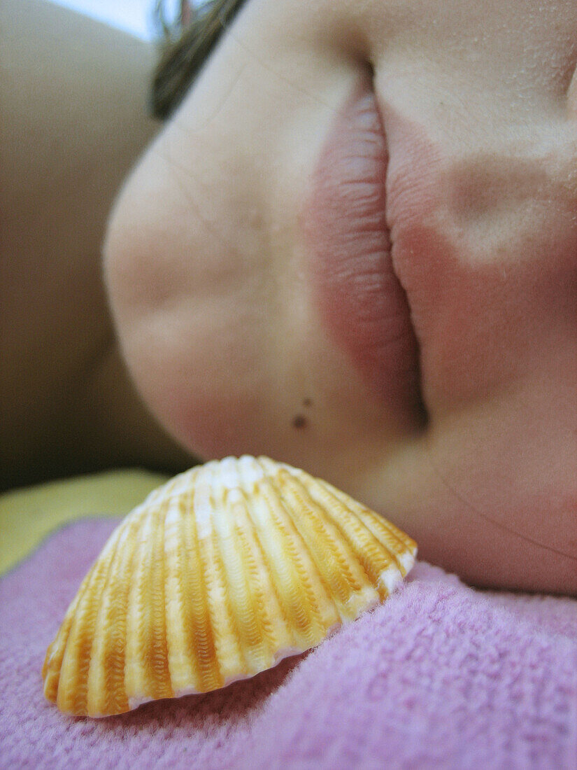 Girls lips beside sea shell