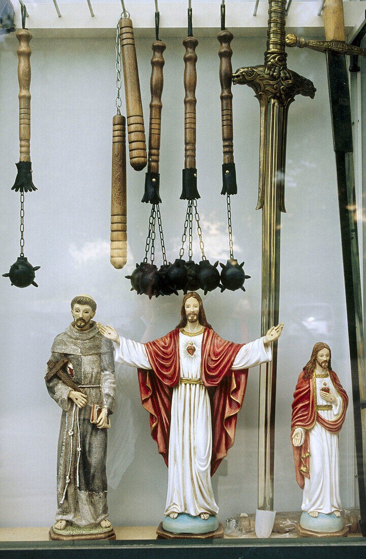 Jesus and weapons in shop window, Gubbio. Umbria, Italy