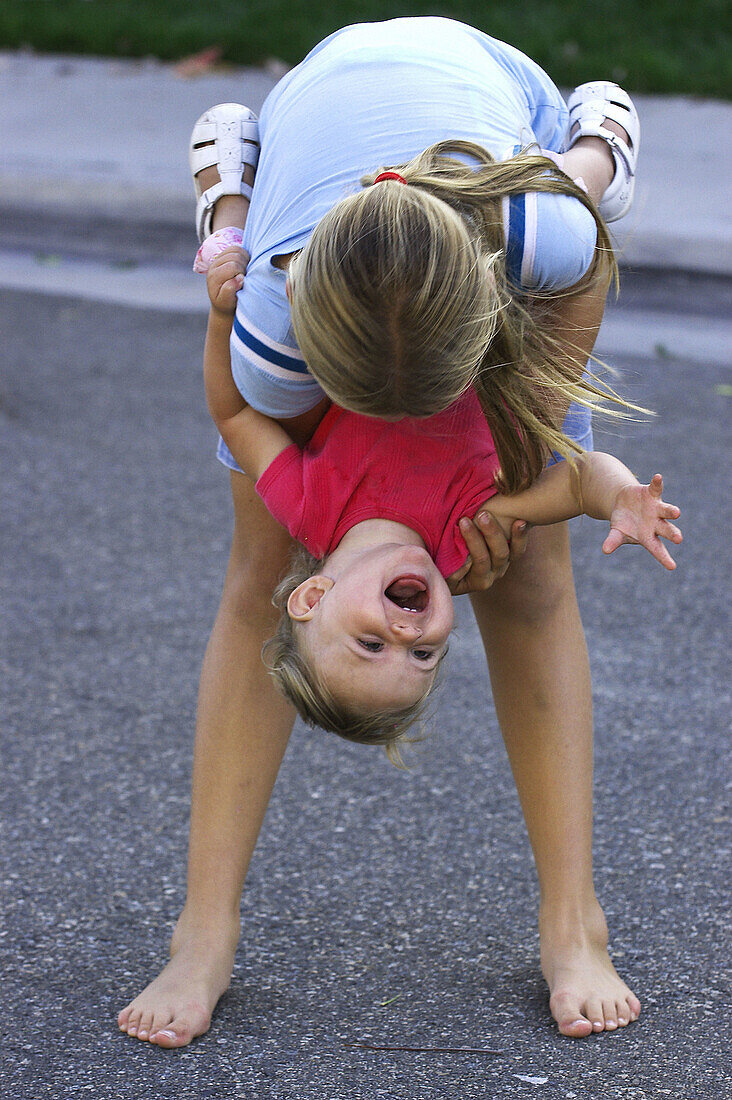 Girl holding laughing toddler upside down