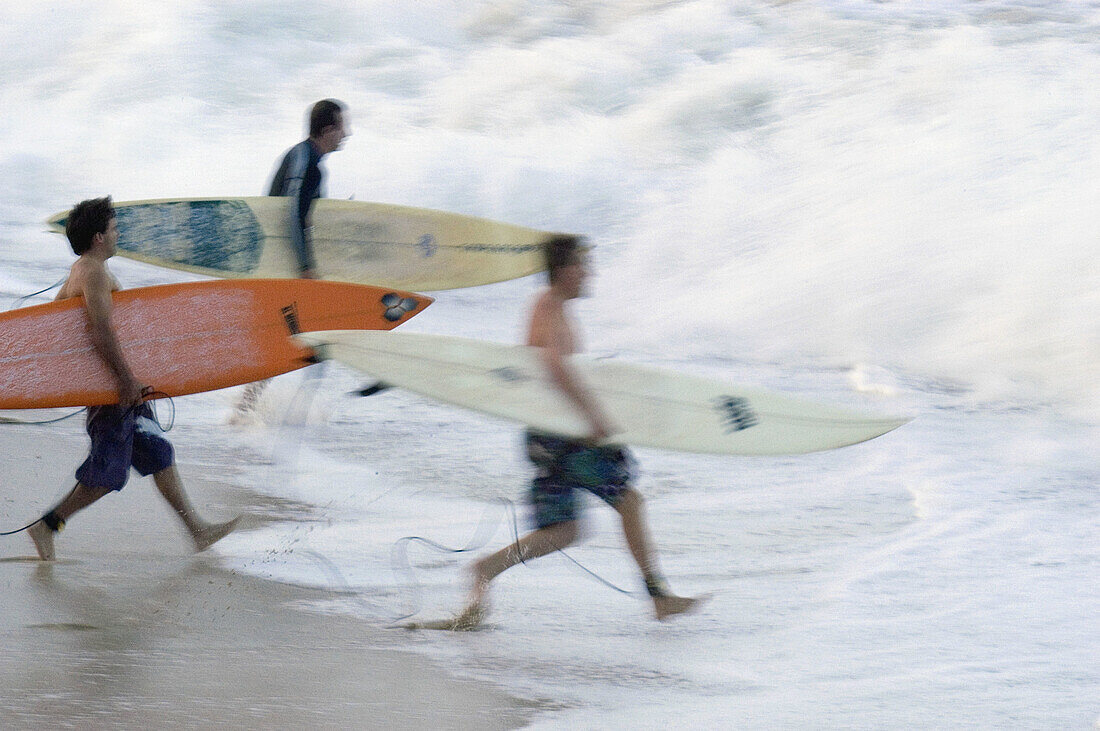Surfers racing into the water