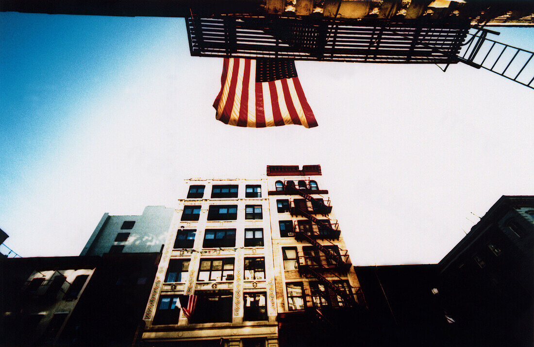  America, American flag, Building, Buildings, Cities, City, Color, Colour, Daytime, Exterior, Fire escape, Flag, Flags, Horizontal, Low angle view, Nobody, North America, Outdoor, Outdoors, Outside, Patriotic, Patriotism, Stairs, Stars and Stripes, U S Fl