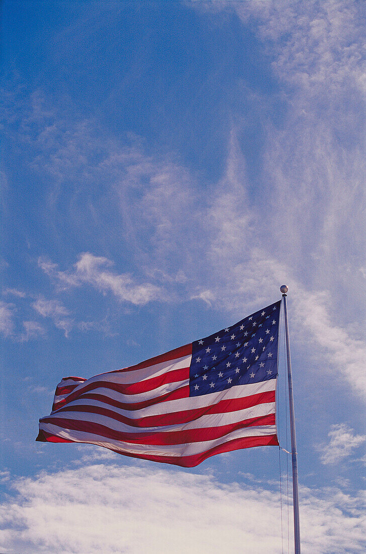 U.S. flag waving against blue sky with cirrus clouds. USA
