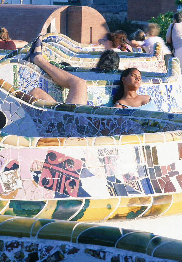 Spain, Catalunya, Barcelona, Young people having a rest at Parc Guell, designed by Antoni Gaudi