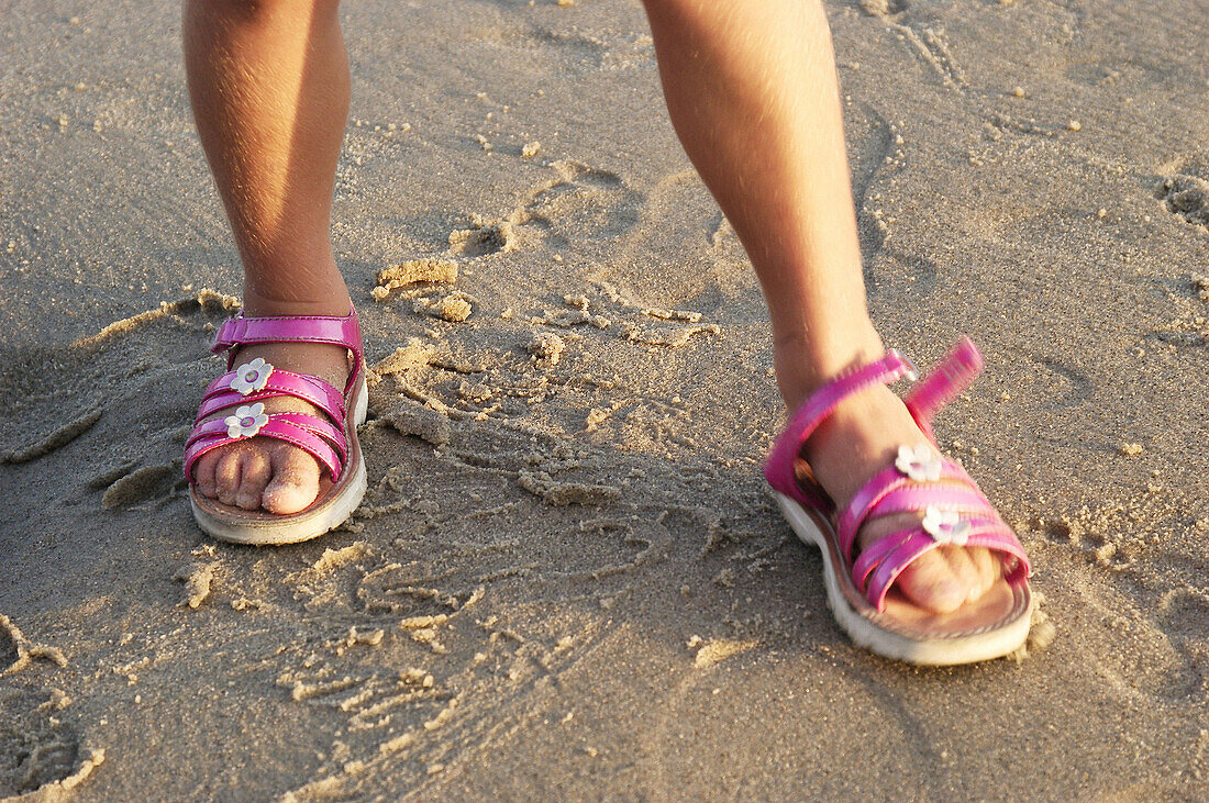 girl with pink sandals at the beach