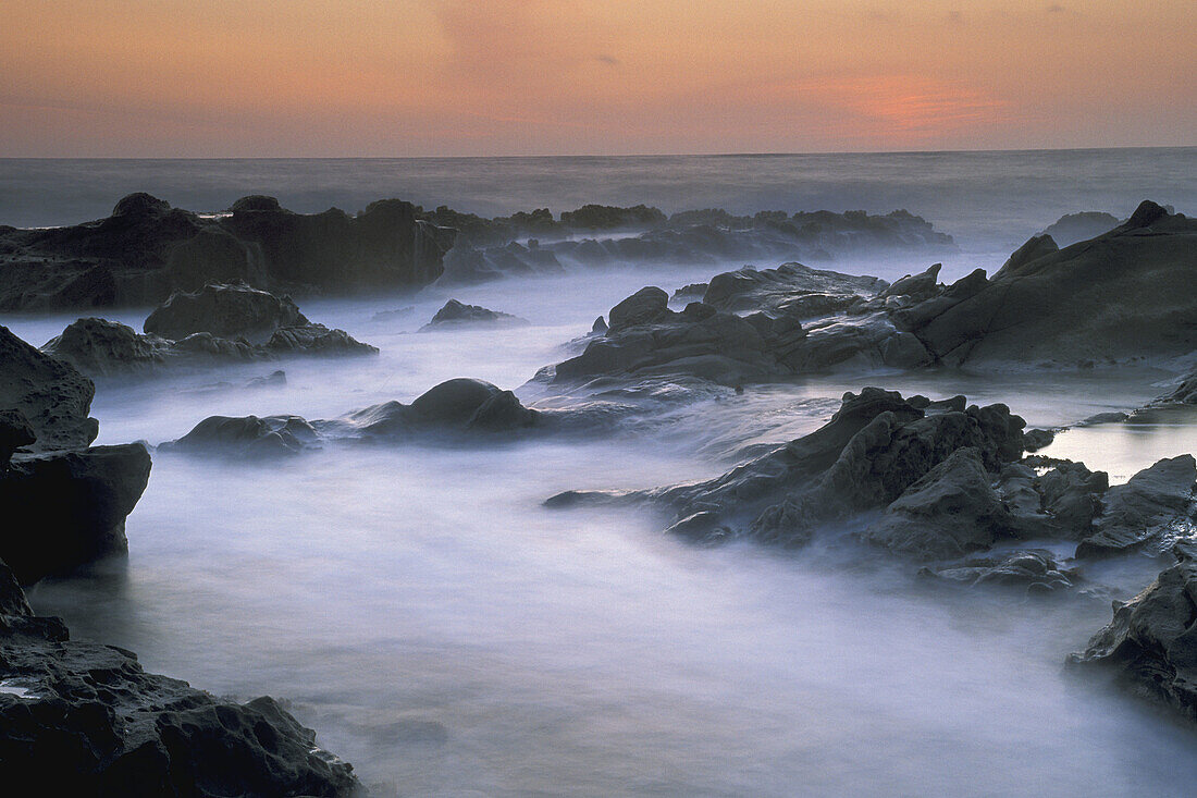 Ocean waves crashing on tidepool rocks at sunset, Bean Hollow State Beach, San Mateo Coast, California