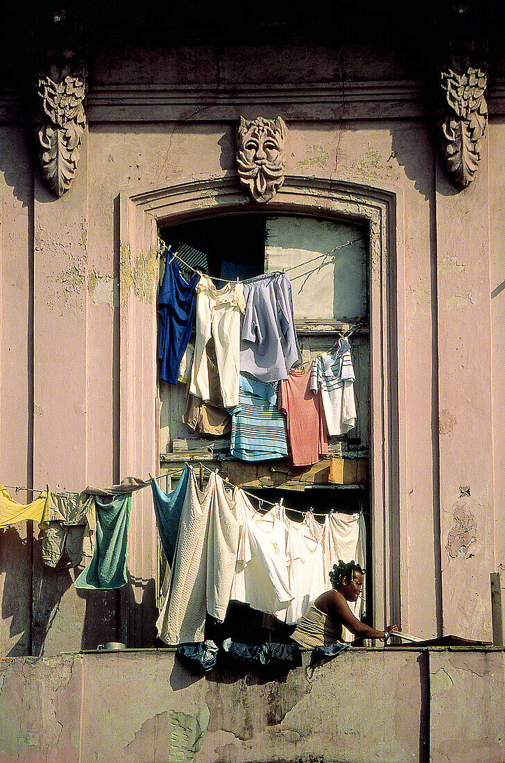 Woman hanging laundry on balcony of old building. Havana. Cuba