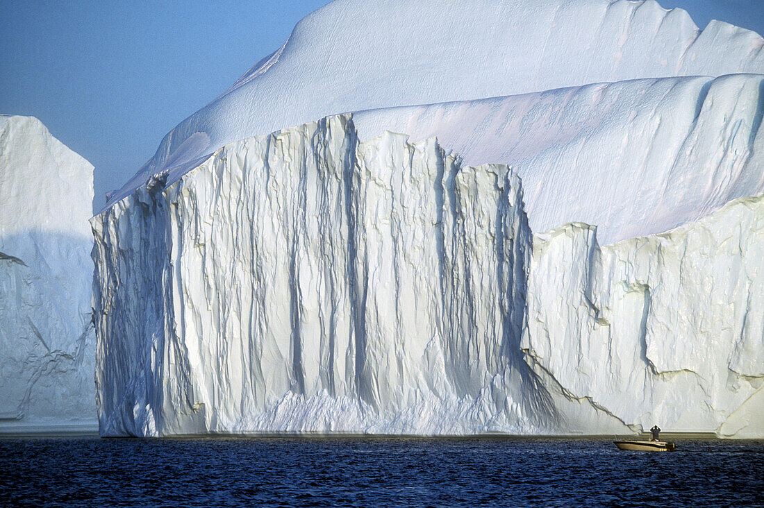 Iceberg detail, man in small boat in foreground. Ilulissat. Greenland