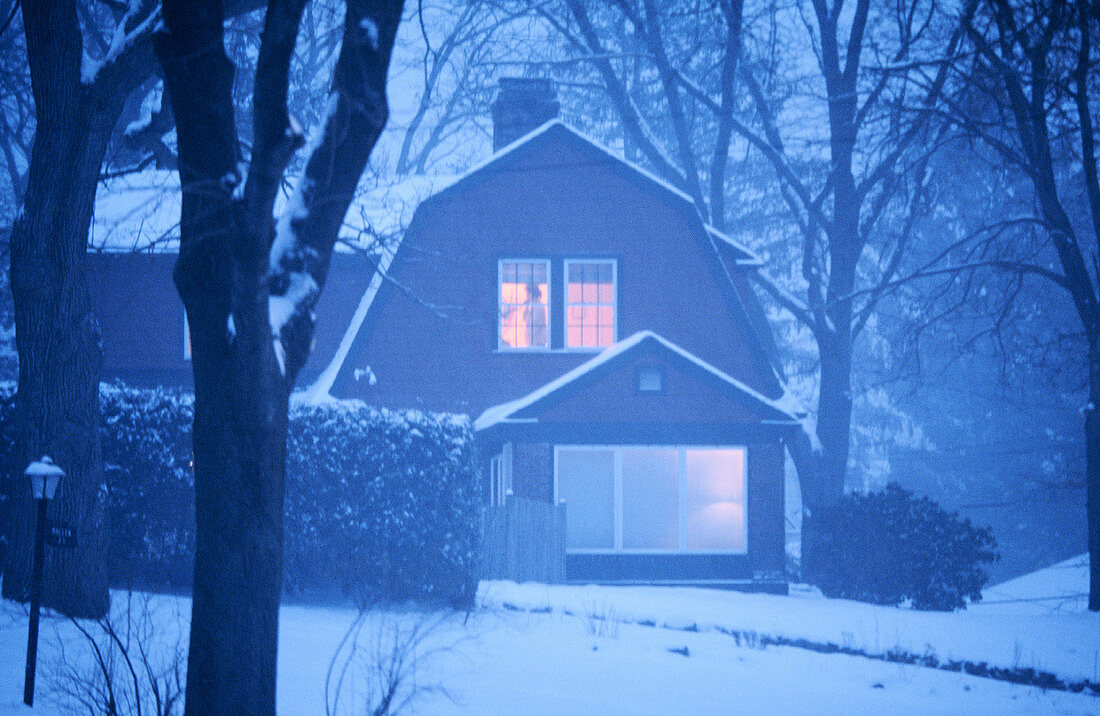 Woman in window at dusk in snowstorm. Winchester. USA