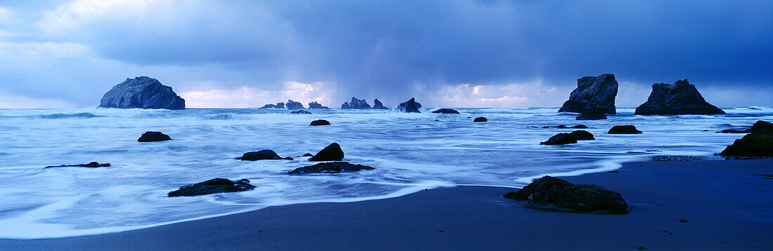 Sunset on horizon below cloud bank at Face Rock State Park. Bandon. Oregon. USA