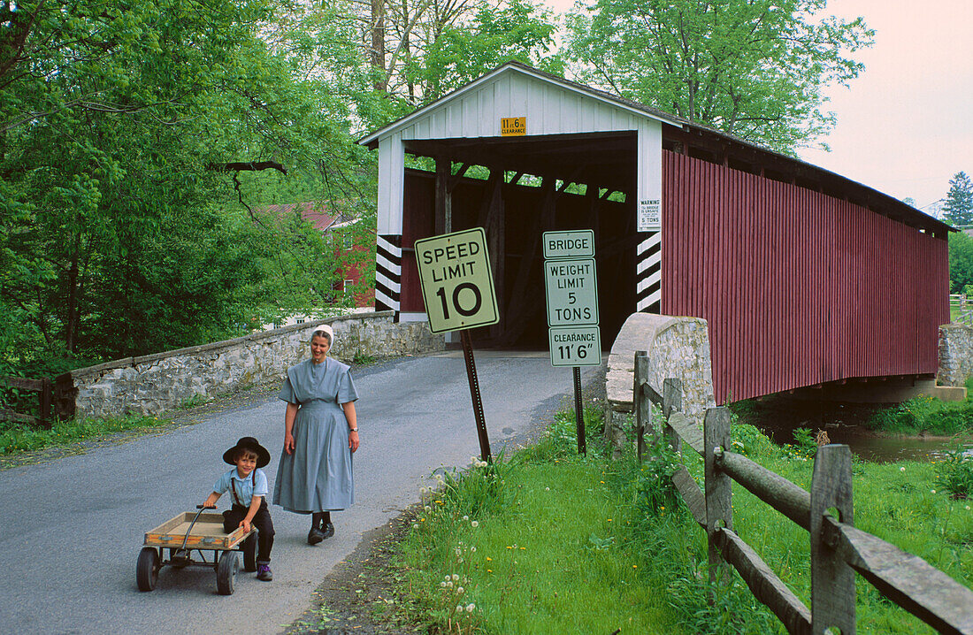 Old Order Brethren mother and son. Historic covered bridge. Manheim. Pennsylvania. USA