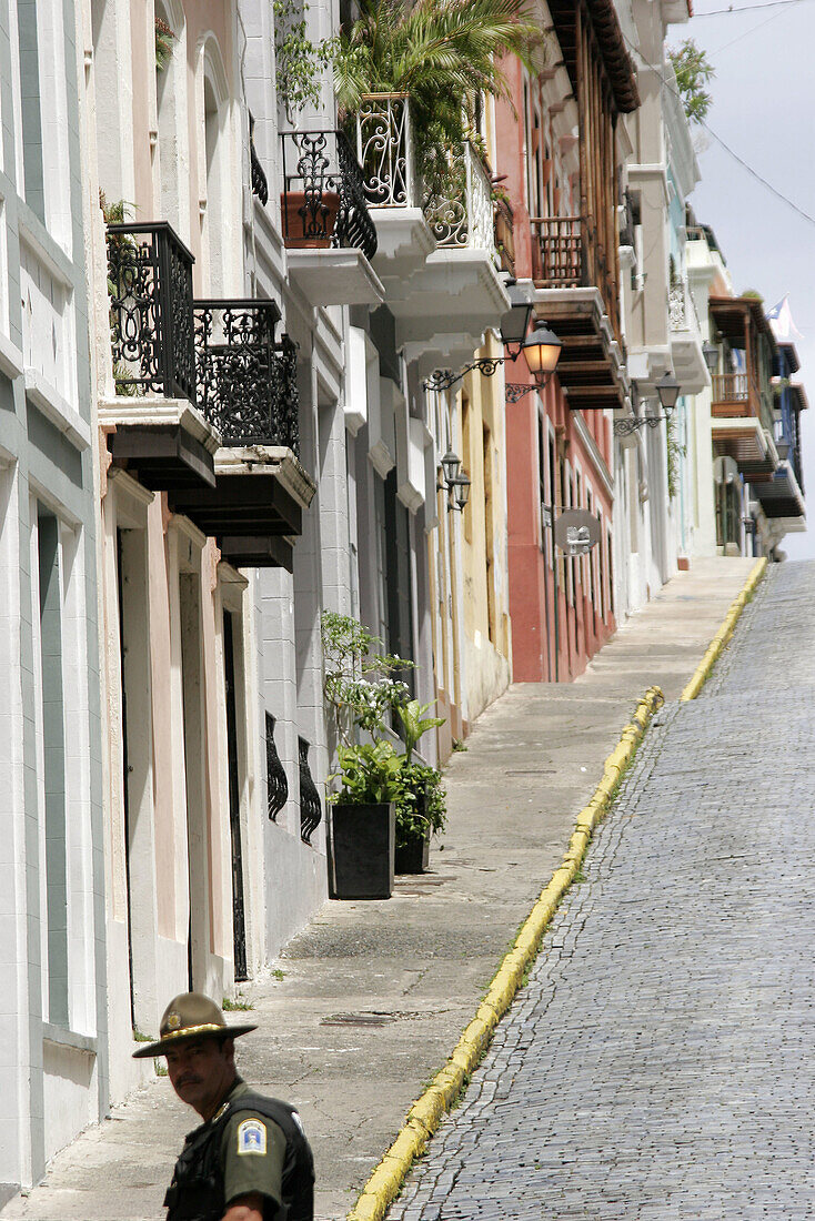 Calle de la Cruz, architecture, steep hill, Hispanic policeman, adoquine cobblestone. Old San Juan. Puerto Rico.