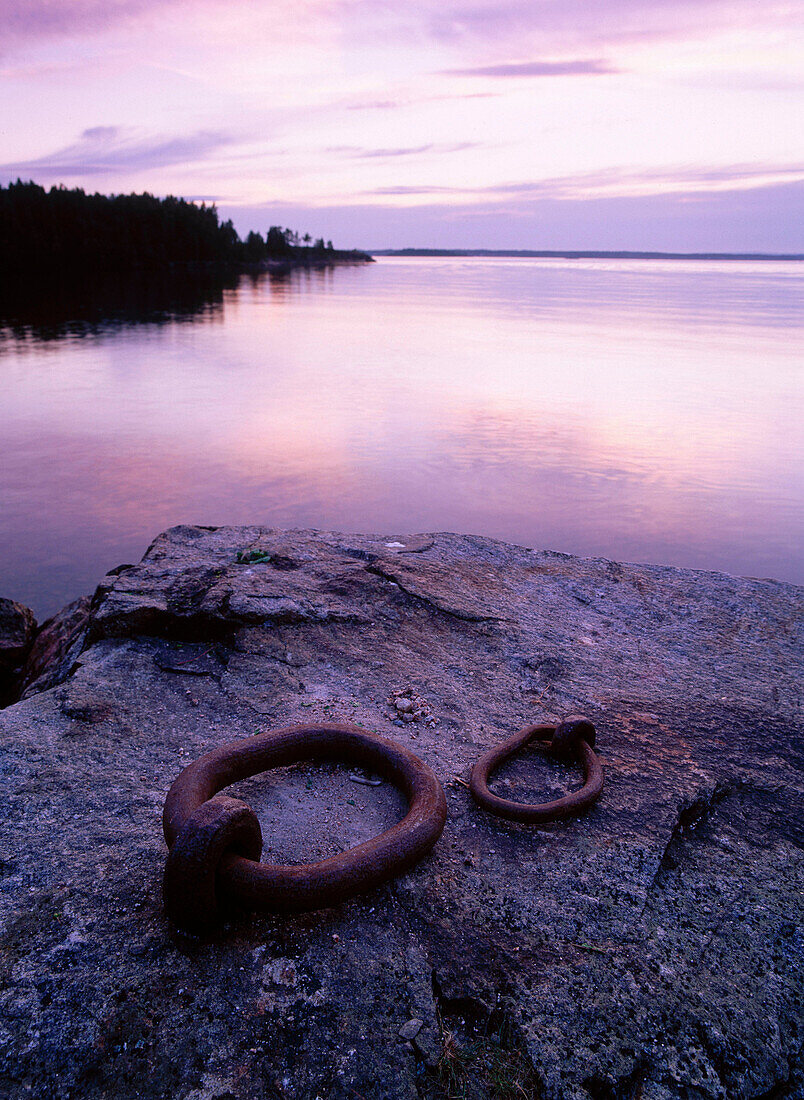 Two old iron rings for big ships at the shore, evening light. Norrbyskär. Västerbotten. Sweden