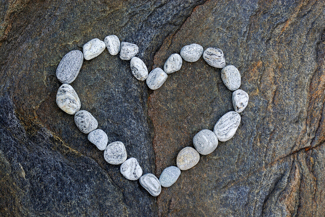 Heart formed with white pebbles on dark rock slab, valley of Verzasca, Verzasca, Ticino, Switzerland