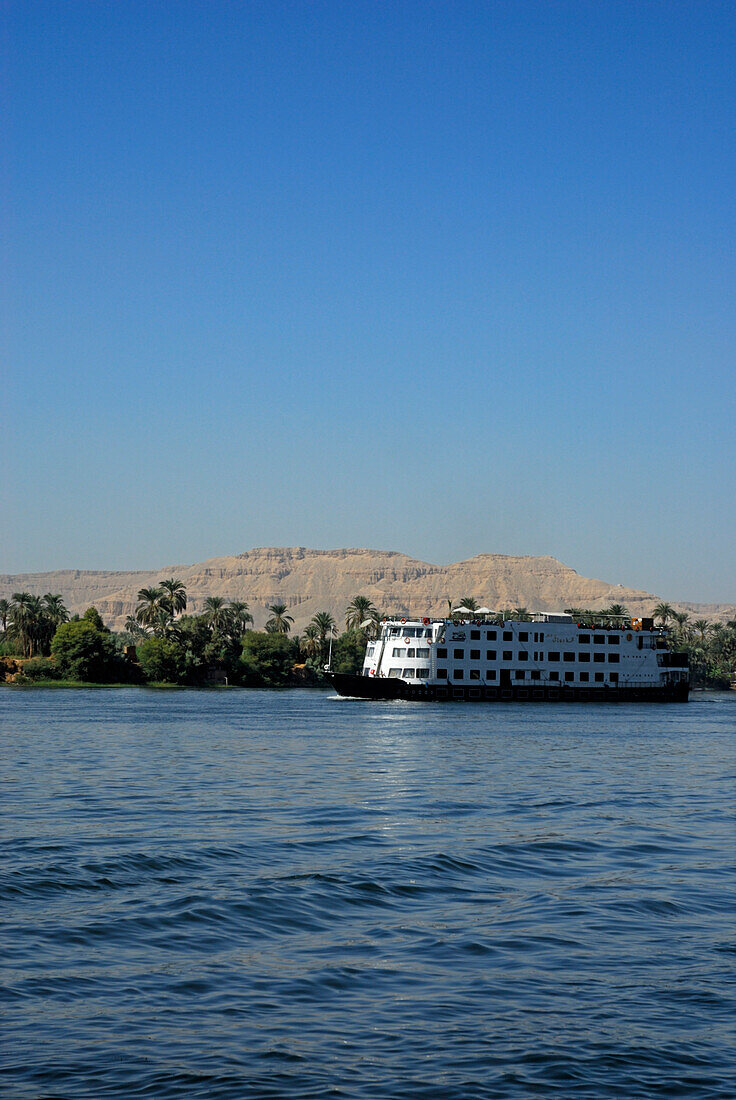 cruise ship on the Nile and palm trees on the western bank, Luxor, Egypt, Africa