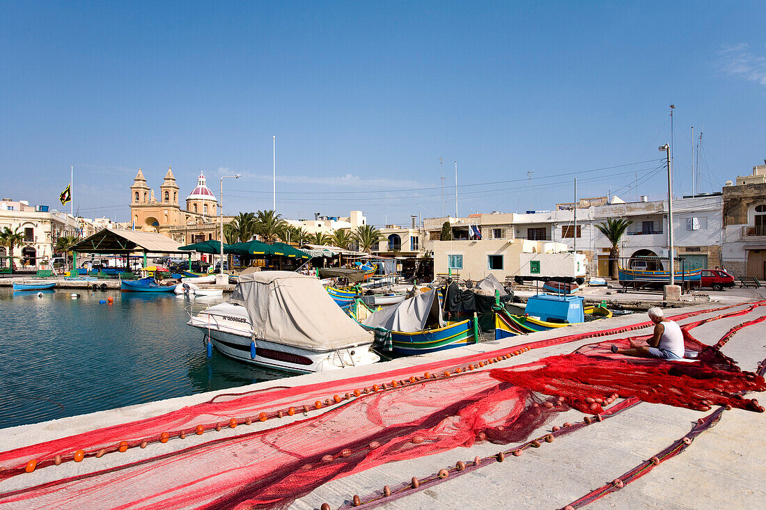 Fischer mit Fischernetz im Hafen von Marsaxlokk, Malta, Europa