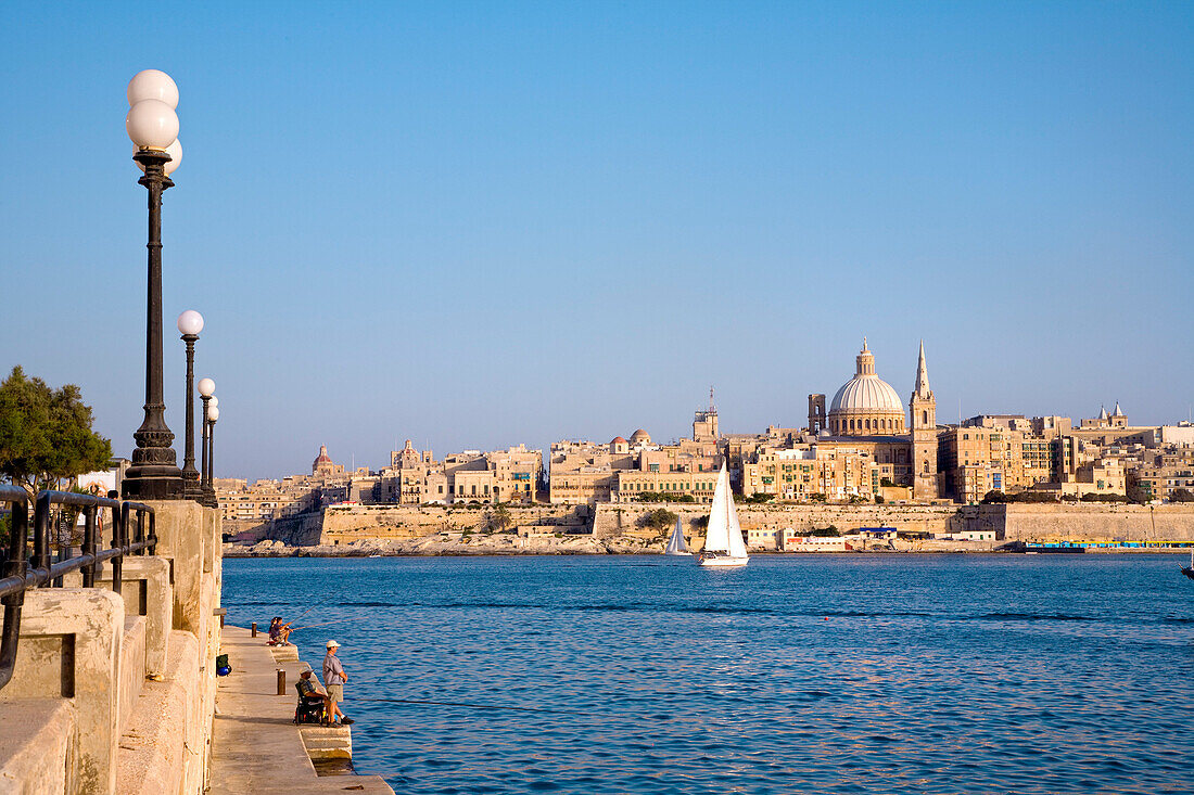 Menschen auf der Uferpromenade von Sliema mit Blick auf die Stadt Valletta, Malta, Europa