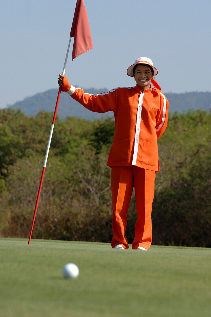 Woman, female caddy holding the flag, Kirimaya Golf Course, Khao Yai National Park, Thailand