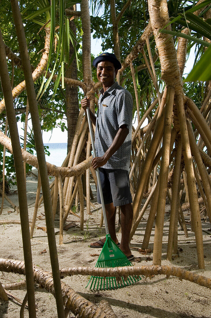 Man, gardener raking the sand, Luxury vacation on a private island with yacht, Rania Experience, Faafu Atoll, Maldives