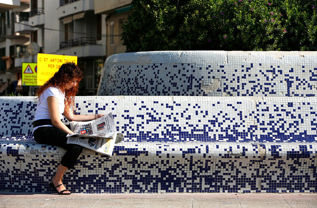 Frau liest in Fußgängerzone, Sitges, Costa de Garraf, Katalonien, Spanien