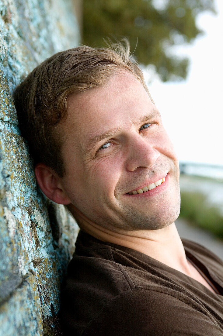 Mid adult man looking at camera while leaning against a wall, Duesseldorf, North Rhine-Westphalia, Germany, Düsseldorf, North Rhine-Westphalia, Germany