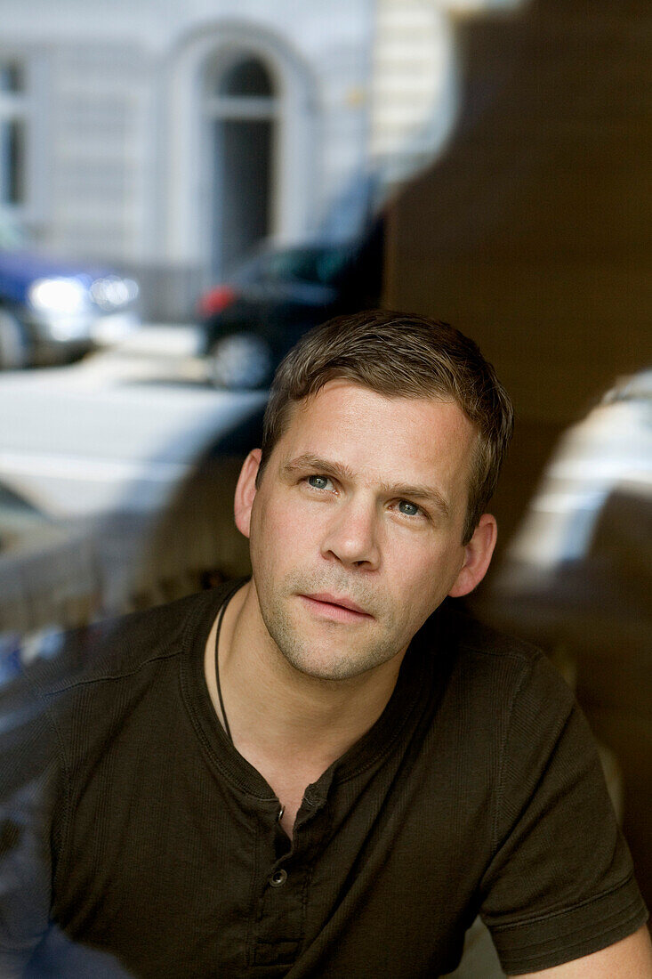 Mid adult man looking through a window of a cafe, Duesseldorf, North Rhine-Westphalia, Germany, Düsseldorf, North Rhine-Westphalia, Germany