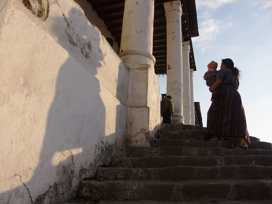 A woman carrying a child enters the main cathedral of San Lucas Toliman, Guatemala, near Lake Atitlán. Guatemala.