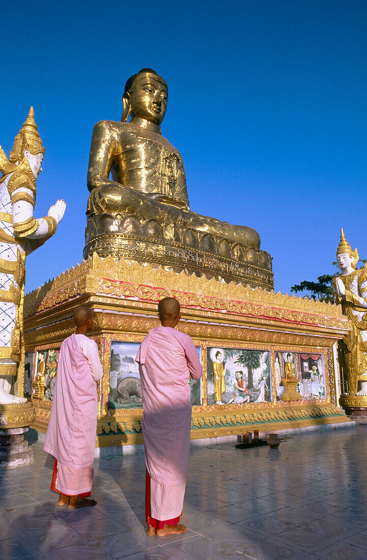 Buddhist nuns praying to Giant Buddha. Sagaing. Mandalay. Myanmar (Burma).