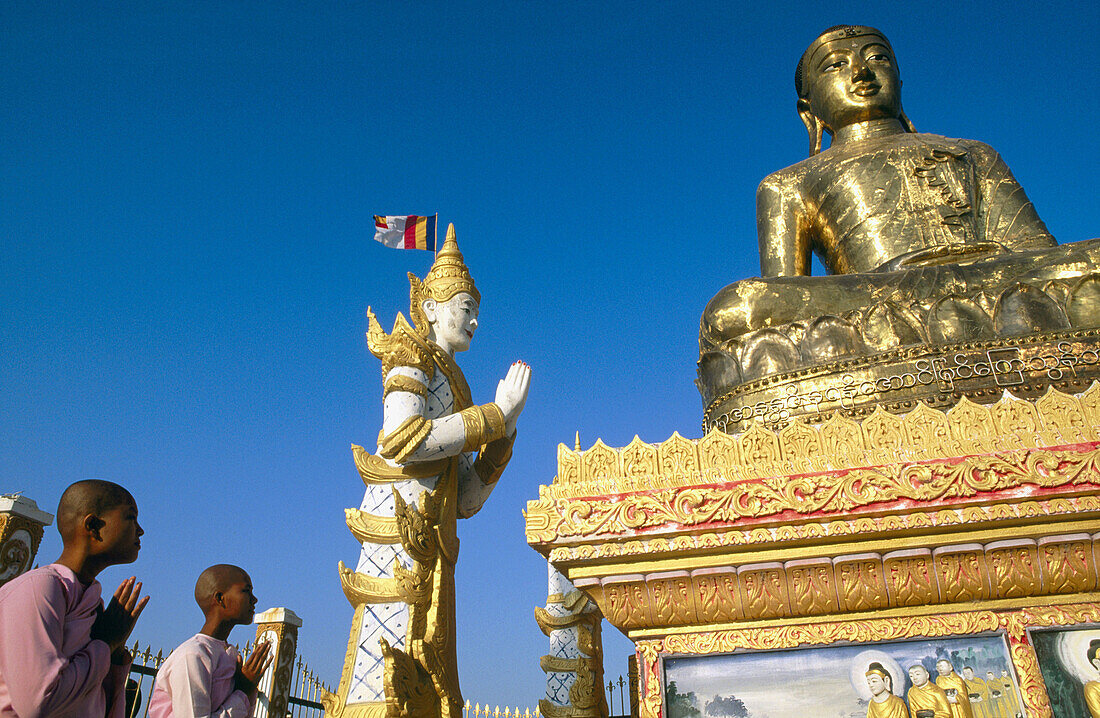 Buddhist nuns praying to Giant Buddha. Sagaing. Mandalay. Myanmar (Burma).
