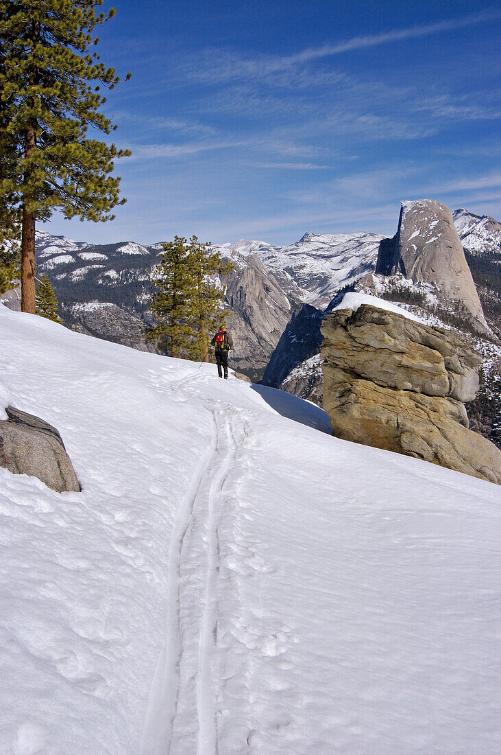 Backcountry skier enjoying the view of Half Dome from Washburn Point, Yosemite National Park, California