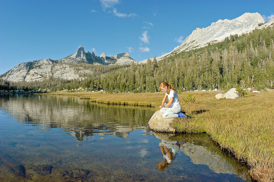 Woman purifying water at Echo Lake under Echo Peaks and Matthes Crest, Yosemite National Park, California