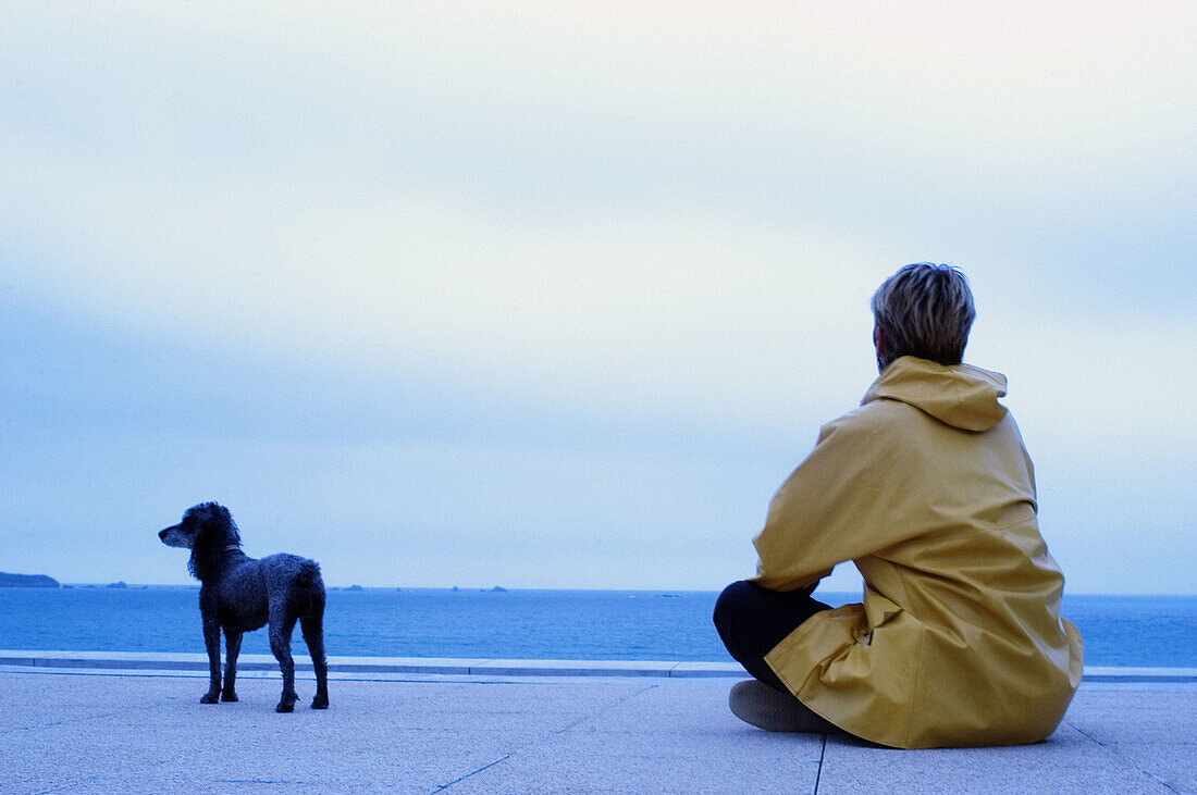  Adult, Adults, Alone, Animal, Animals, Baby boomer, Baby boomers, Back view, Blue, Calm, Calmness, Color, Colour, Companion, Companions, Contemporary, Daytime, Dog, Dogs, Exterior, Female, Full-body, Full-length, Future, Ground, Grounds, Horizon, Horizon