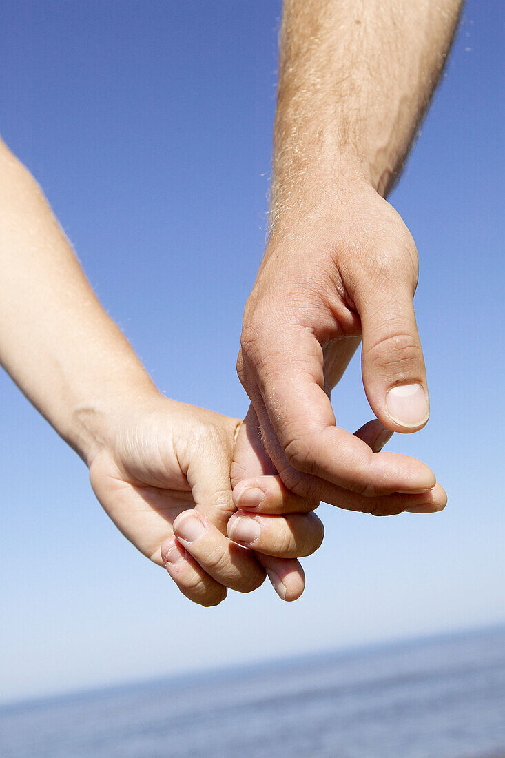 Man and woman holding hands on beach. Skåne. Sweden