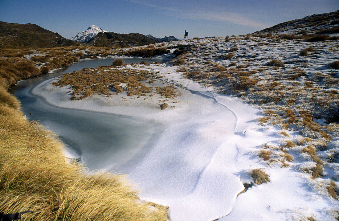 Tramper near frozen tarn. Kelly Range. Arthur s Pass NP. New Zealand