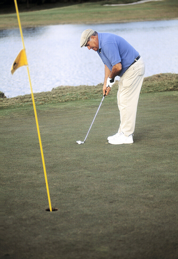 Mature man playing golf on the green