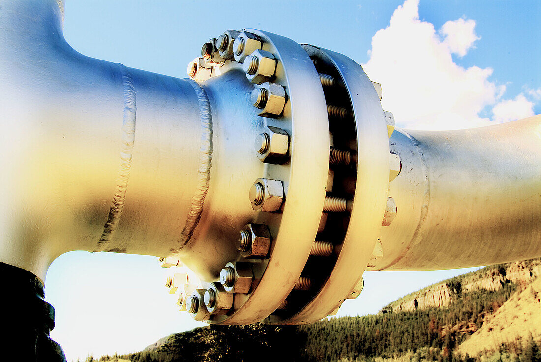 Nuts and bolts holding together pipeline, sky in background